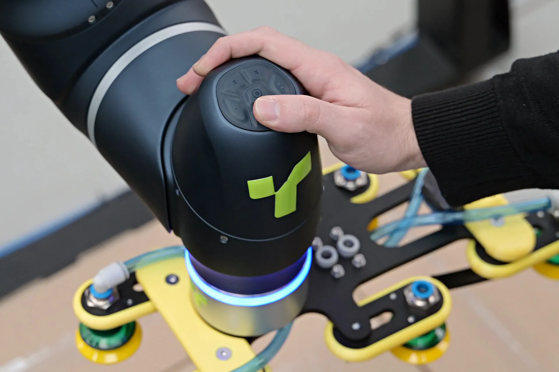 Operator hand-guiding the TRFCobot collaborative robot arm and vacuum gripper.