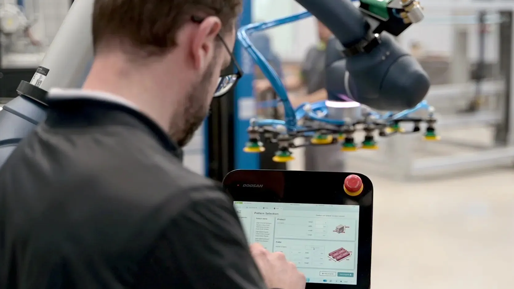 Operator setting a recipe on the TRFCobot touch screen while the collaborative robot works nearby.